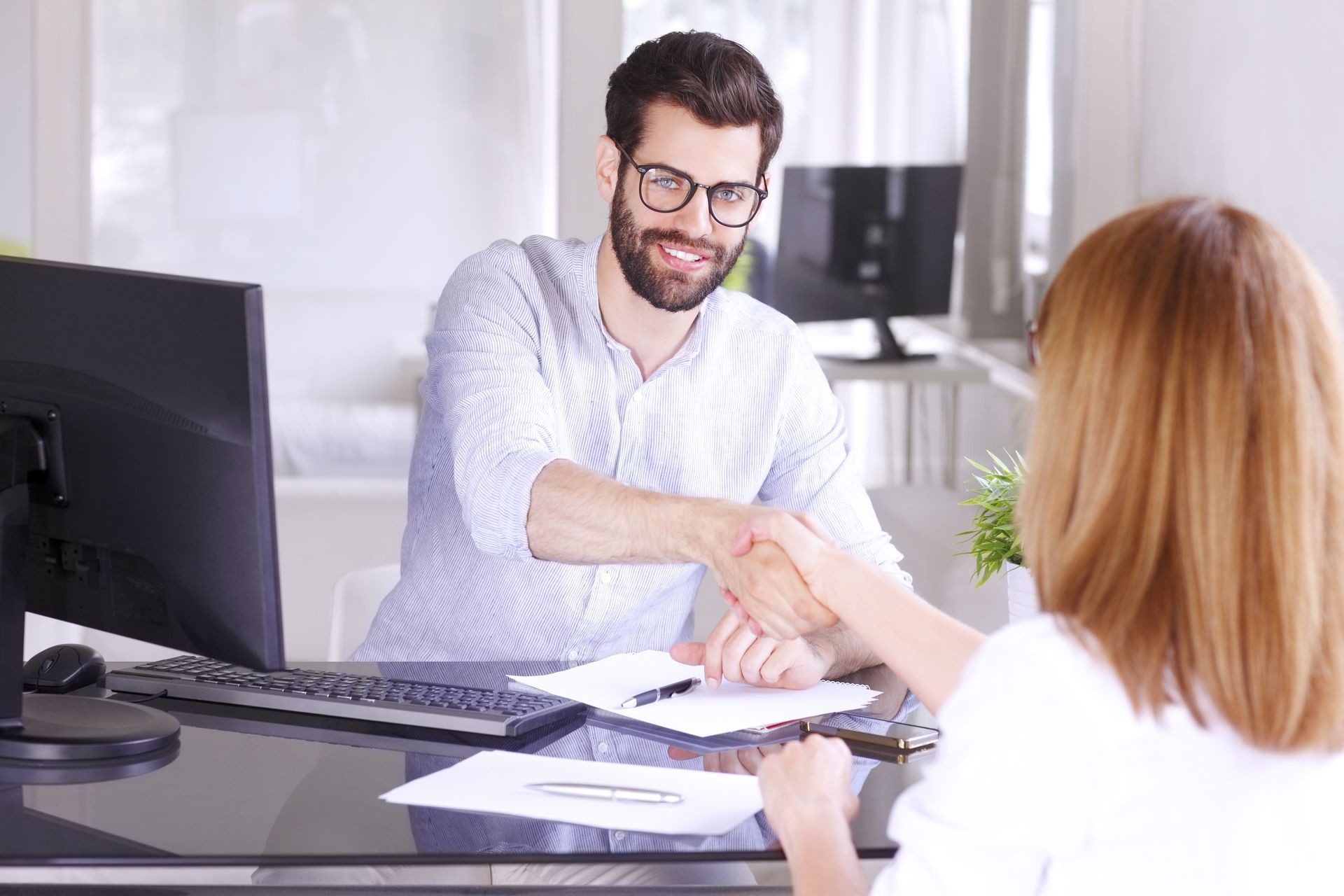 business people shaking hands while sitting in front of computer and working together OWC business relationships